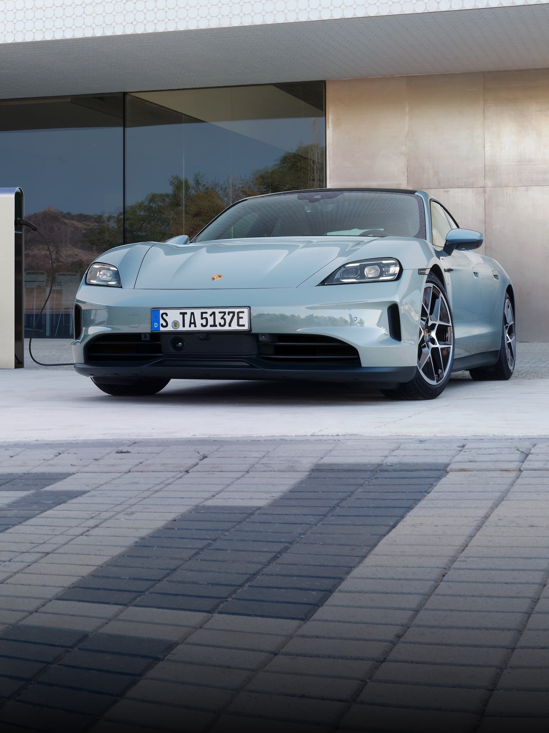 Ein Porsche Taycan parkte draußen vor einem modernen Gebäude.